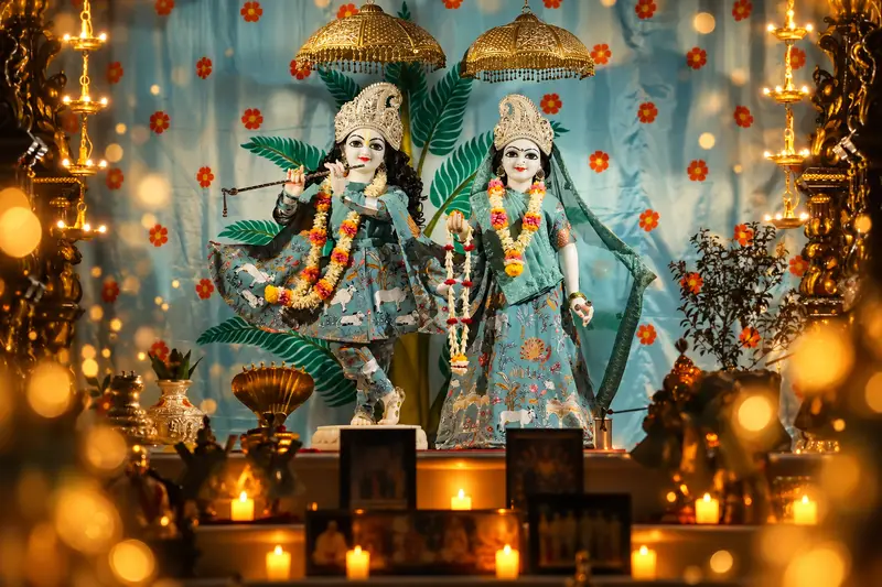 Sri Sri Radha Vrindavan Chandra in the sea-green Kartik poshak, lamps lit all around the altar
